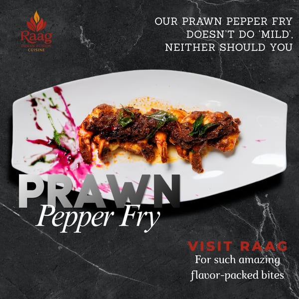 Raag's Prawn Pepper Fry, a dish of spicy prawns garnished with green leaves on a white plate.